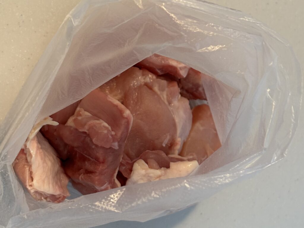 一口大に切った鶏もも肉をポリ袋に入れた様子。下味をつける前の準備段階。