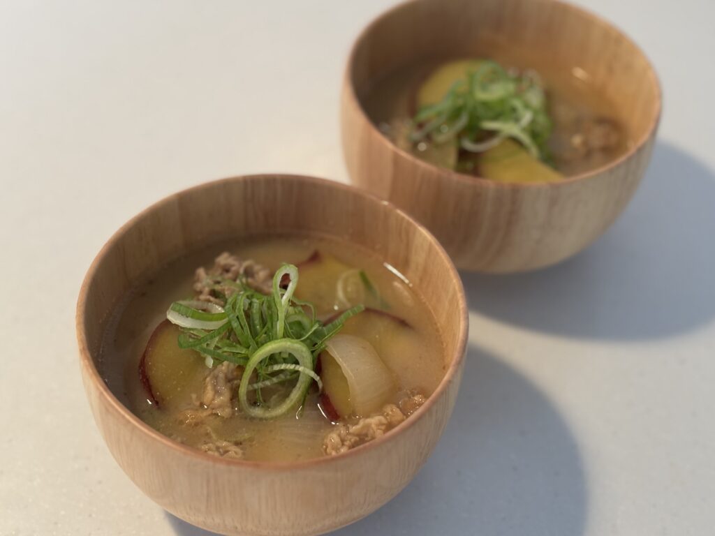 バーミキュラ ユキヒラで作った豚肉とさつまいもの味噌汁を木製の器に盛り付けた和食レシピ。仕上げにネギをトッピング