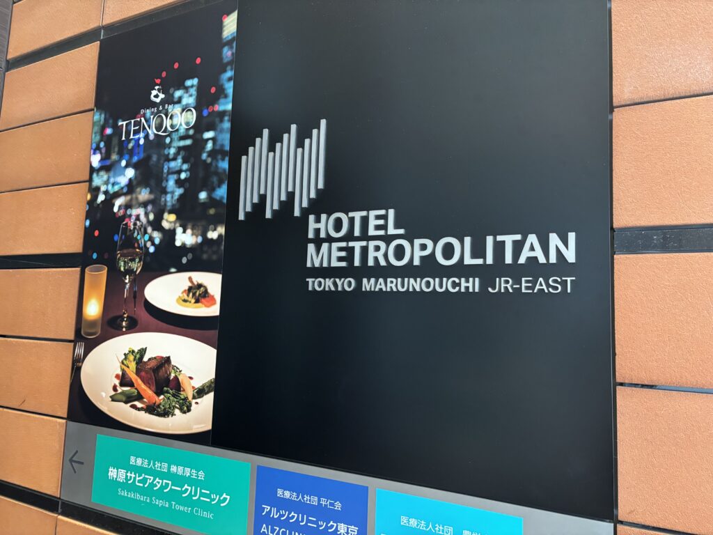 ホテル外観サイン「ホテルメトロポリタン丸の内とダイニング&バー『TENQOO』の案内看板。東京の夜景とフレンチ料理の写真付き。」