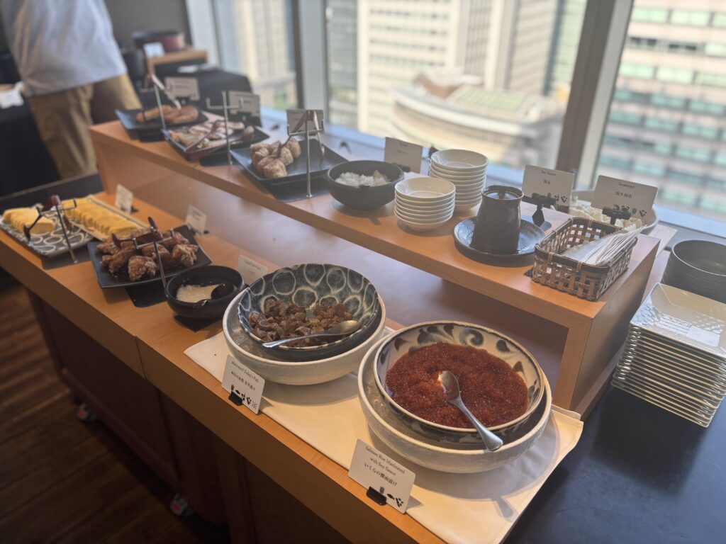 朝食ビュッフェ 和食コーナー①「ホテルメトロポリタン丸の内の朝食ビュッフェ。卵焼き、唐揚げ、いくら、筑前煮などの和食料理が並ぶ。」