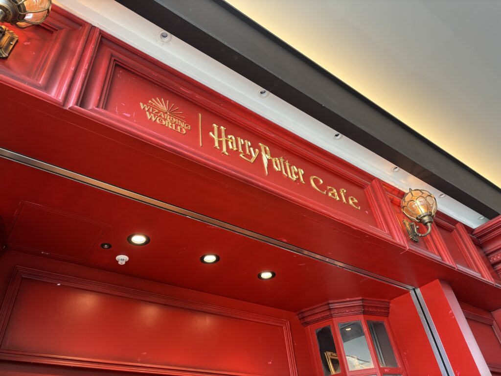 Harry Potter Cafeの入口上部、鮮やかな赤い壁にゴールドのロゴが輝く外観