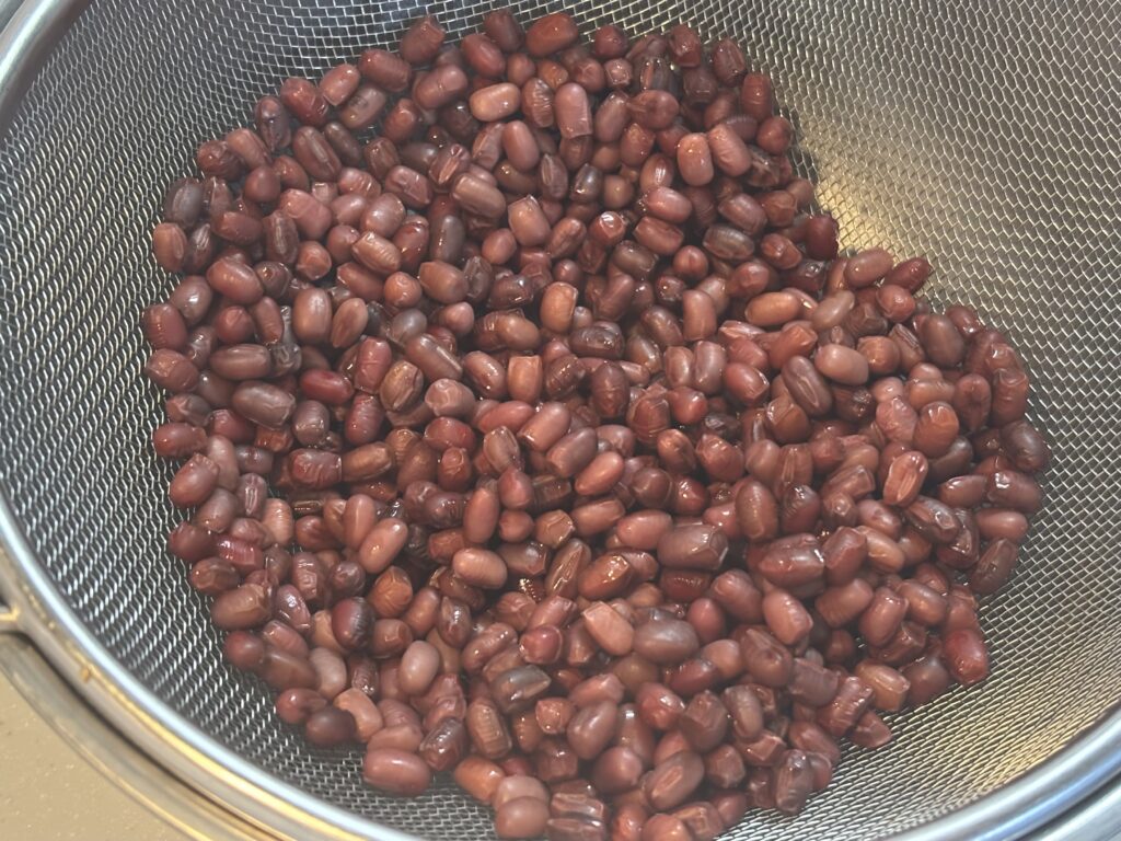 下茹でした小豆を金属製のザルにあけて水気を切っているところ①