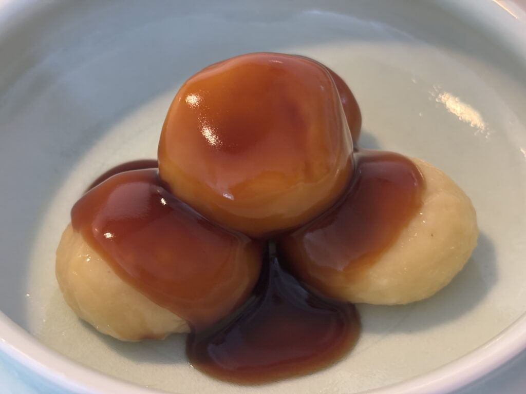 みたらし団子のクローズアップ
団子3つに絡んだタレのアップ。表面が輝き、しっとりとした食感が伝わる。