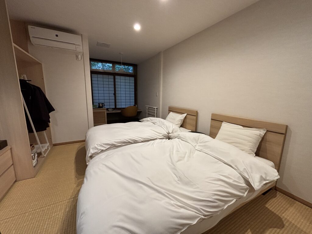 嬉野温泉 吉田屋のツイン客室。和モダンの落ち着いた部屋にベッドと広めのデスクが配置された快適な空間。