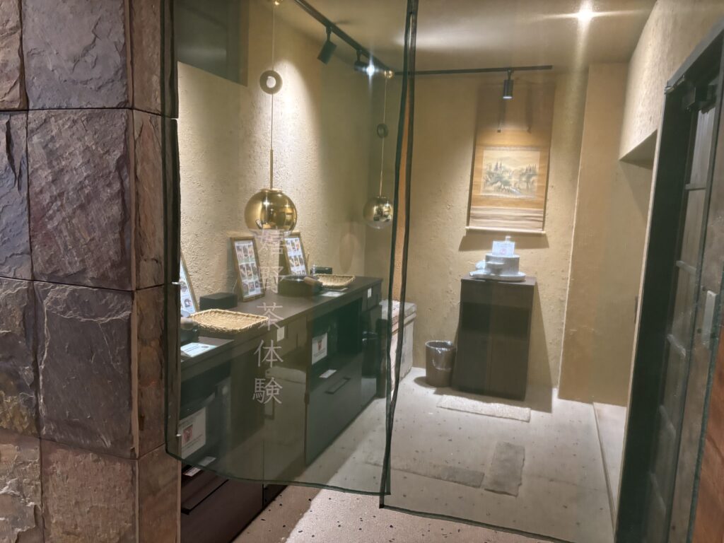  お茶体験コーナー（部屋入口のガラス越し）嬉野温泉 吉田屋のお茶体験コーナー。手もみ茶や煎じ茶体験ができる和の空間で、落ち着いた照明が印象的。