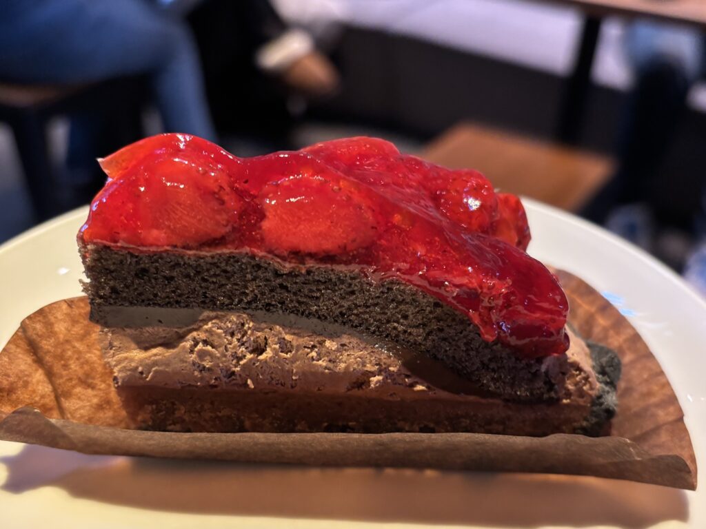 ストロベリー＆チョコレートタルトの断面アップ写真。チョコレートムースと生地の層に、ストロベリーソースが重なる。ストロベリーソースが輝いている。